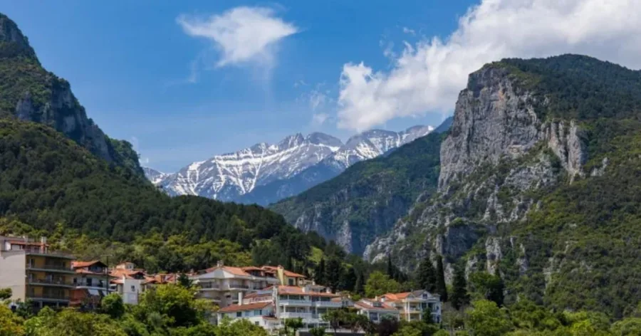 Τα σπίτια του Λιτοχώρου στην είσοδο του δασωμένου φαραγγιού, με χιόνι στις ψηλές κορυφές πίσω